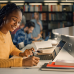 Happy female university student studying in library with laptop and notebooks using Randburg self storage for student belongings